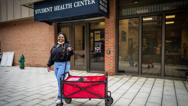 A student stands by a red cart in front of Georgetown's Student Health Center