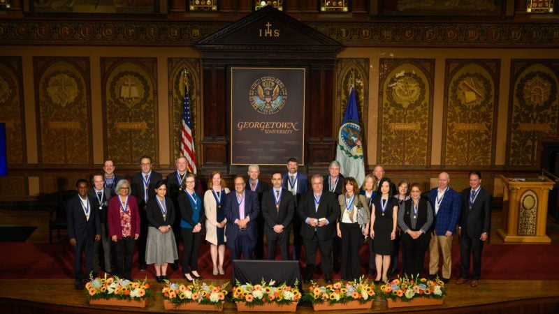 A group of awardees pose on the stage of Gaston Hall