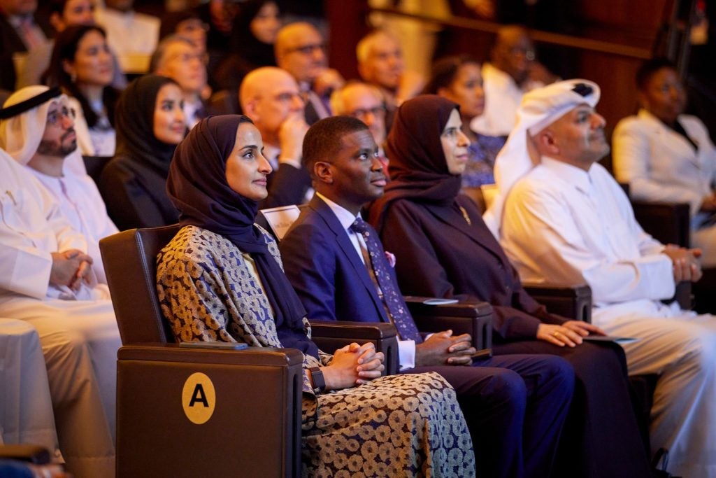 A group of audience members look up at a stage