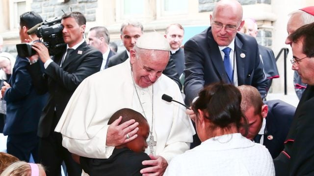 Pope Francis greets and hugs a child