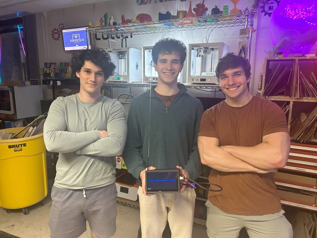John Andrzejewski (C'25), Eli Kerstein (C'24) and Lucas Raskin in a physics lab with a piece of equipment