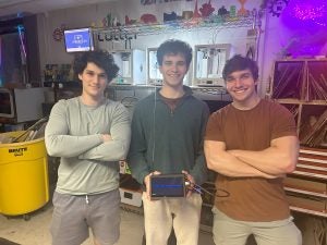 John Andrzejewski (C'25), Eli Kerstein (C'24) and Lucas Raskin in a physics lab with a piece of equipment