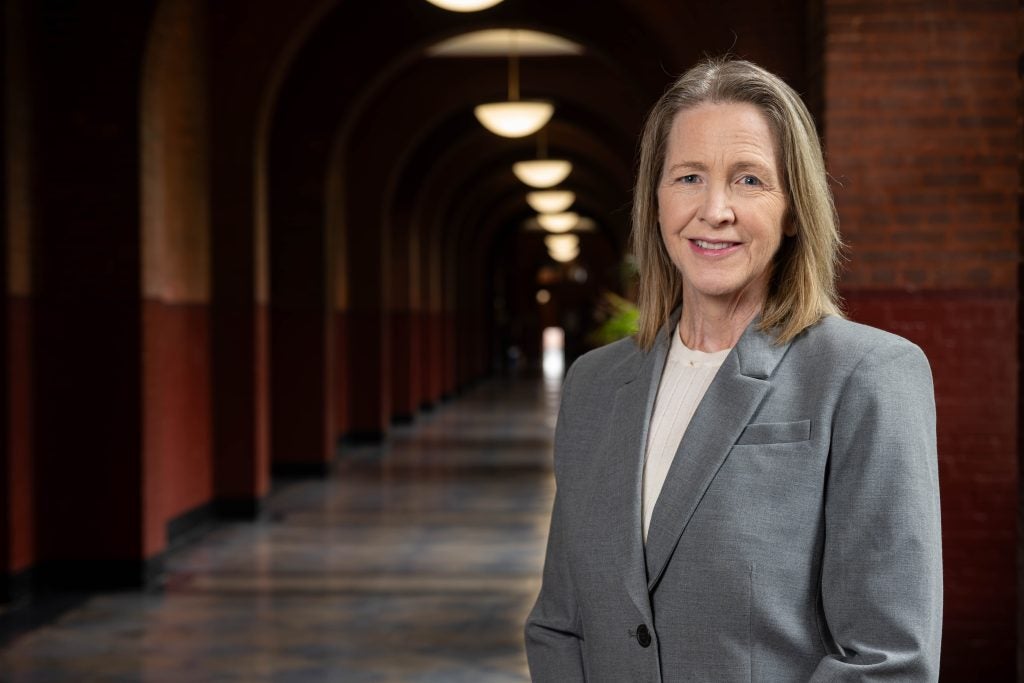 Carole Gresenz in a gray suit smiling inside Healy Hall