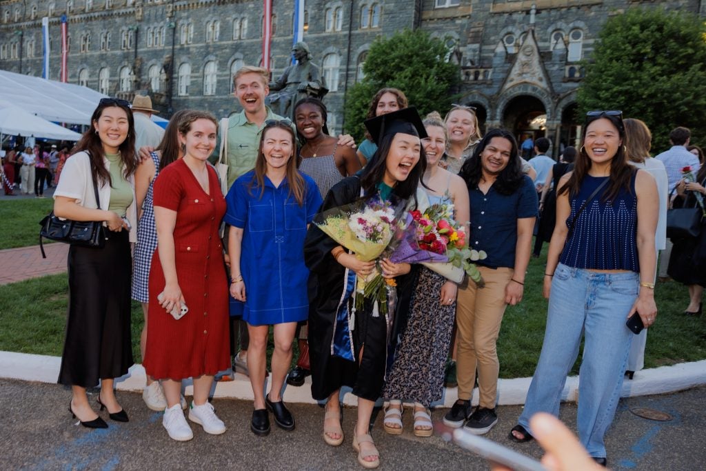 A young Asian women in graduation regalia with her friends