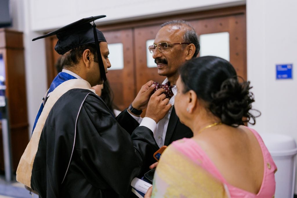 A young graduate adjusts his father's bow tie