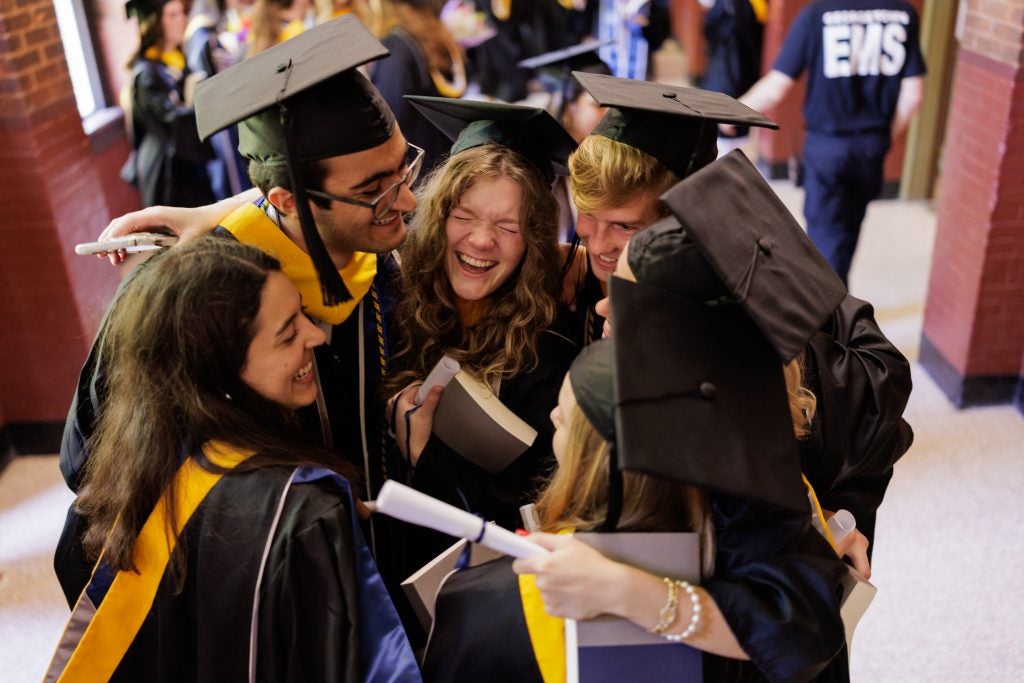 A group of graduates embrace in a hallway