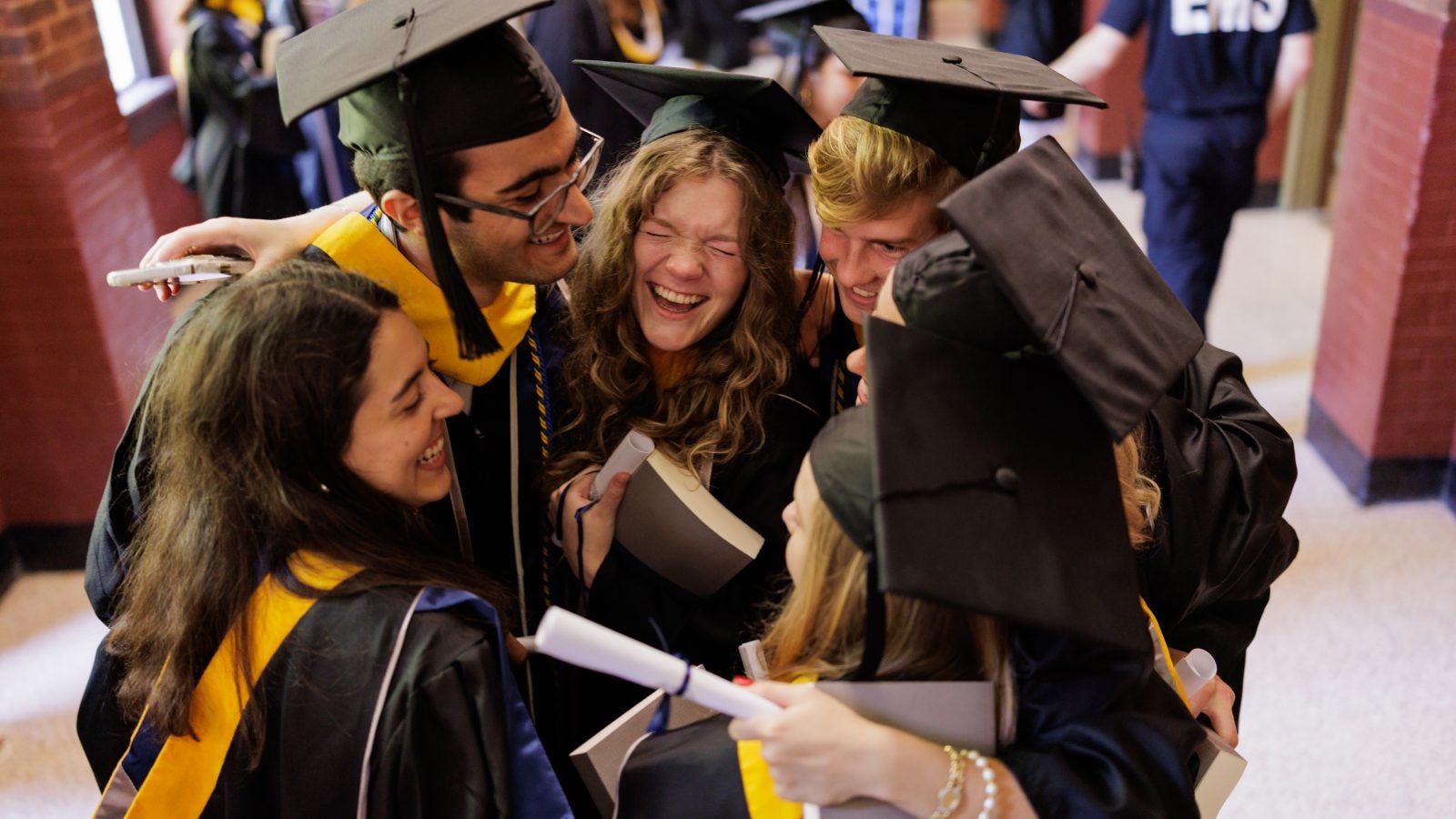 A group of graduates embrace in a hallway