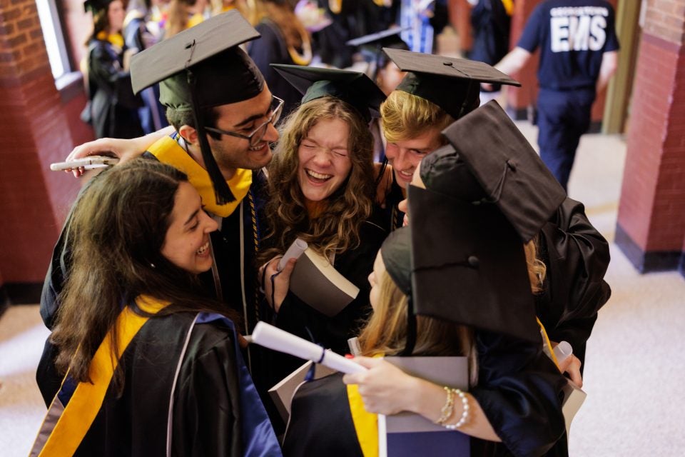 A group of graduates embrace in a hallway
