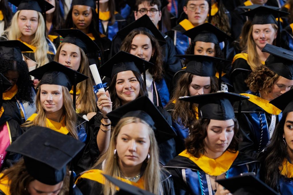 A young woman holds her diploma