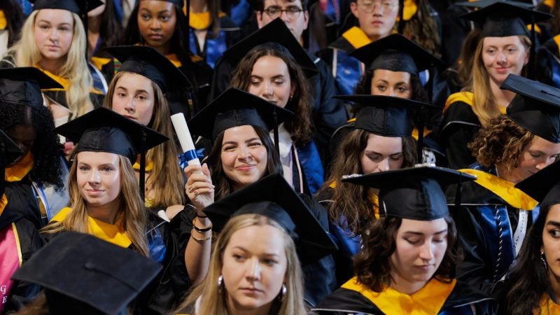 A young woman holds her diploma