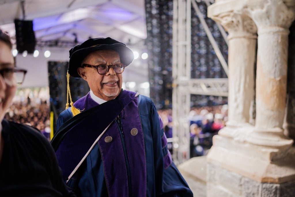 Henry Louis Gates wears a graduation cap and gown onstage