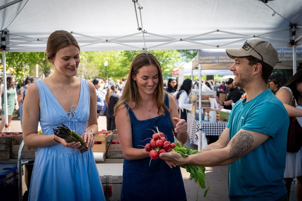 A young man hands some produce to two young women