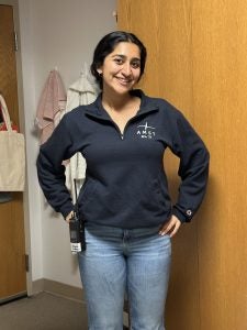 Harnoor in a sweatshirt in a dorm room