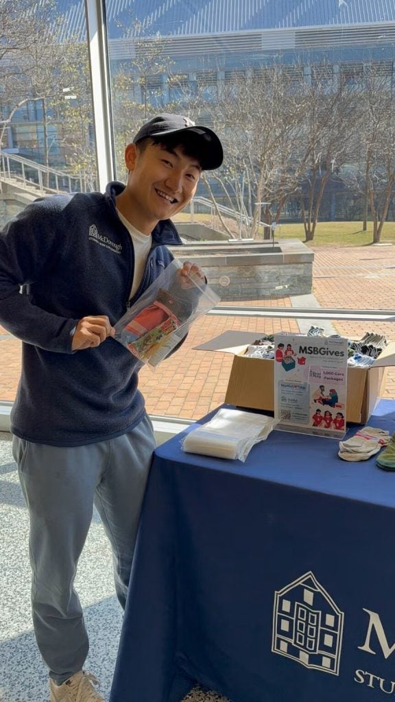 Young Asian man stands by a table