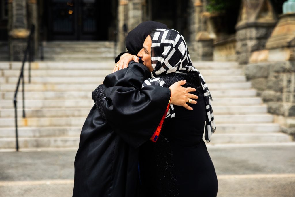 A mother and a daughter hug each other in front of stone steps