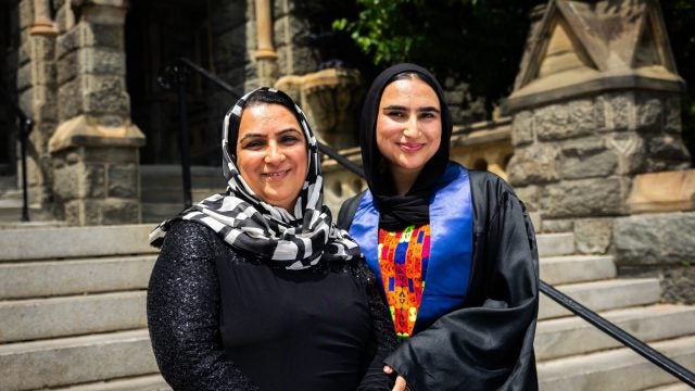 A mother and daughter both wear hijabs and smile on stone steps