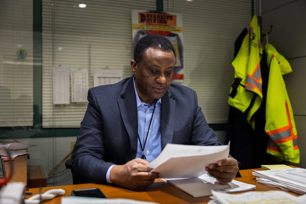 A man in a suit looks at papers at his desk