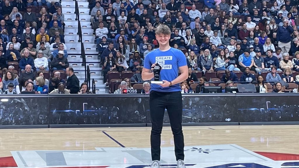 Young man stands with a trophy in a basketball arena