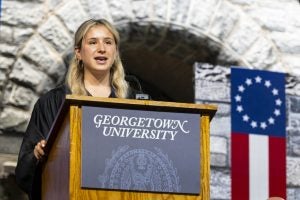 A young white woman speaks at a podium at graduation
