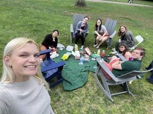 Lisa with students sitting in Adirondack chairs on the lawn
