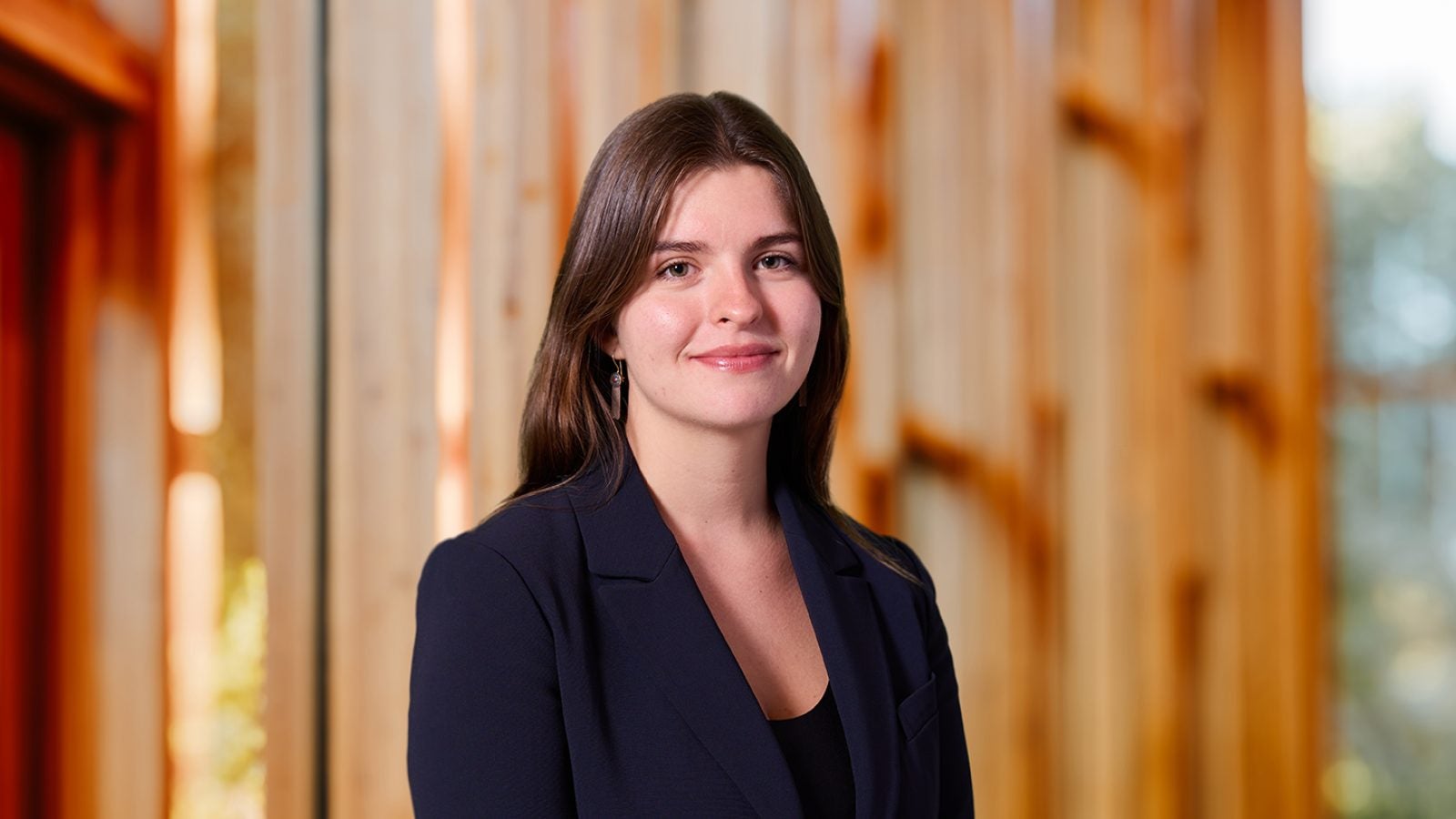 A woman with brown hair and a black blazer smiles