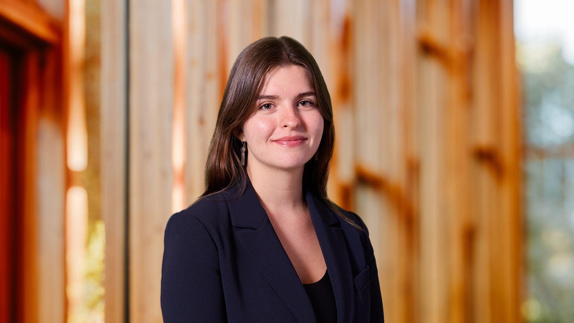A woman with brown hair and a black blazer smiles