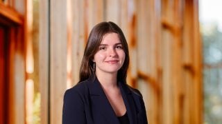A woman with brown hair and a black blazer smiles