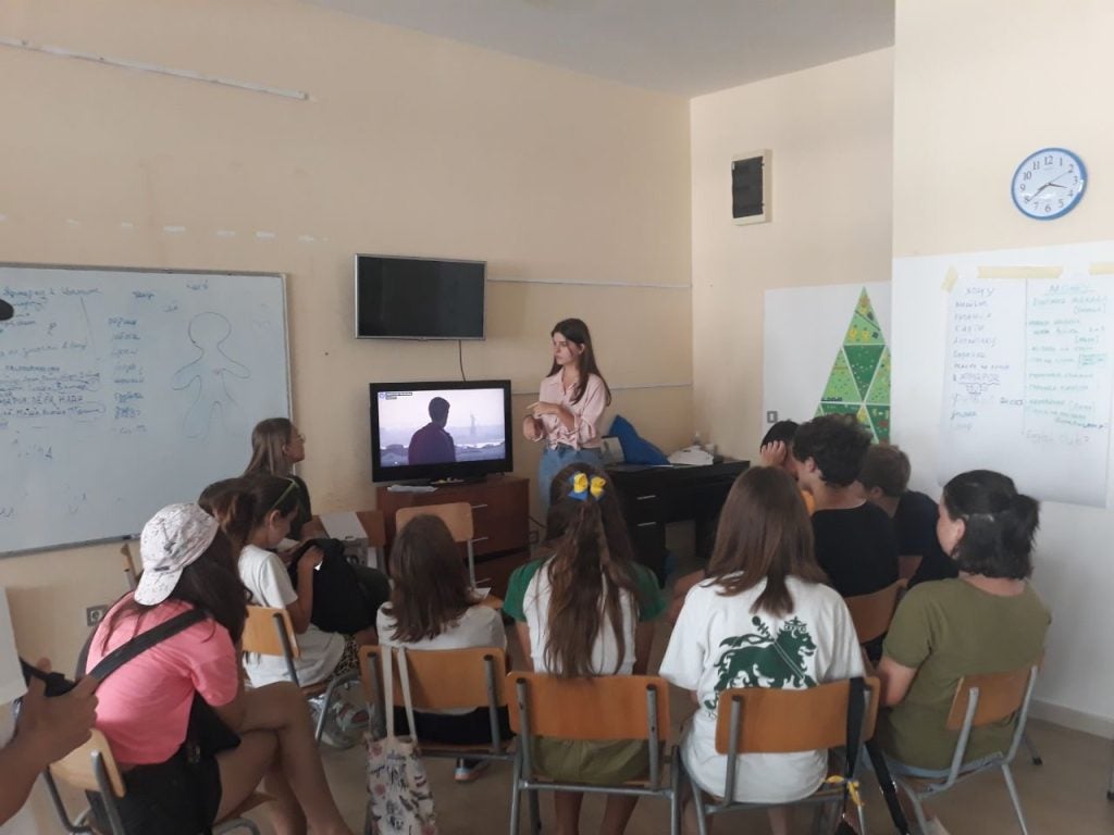 A student teaches Ukrainian teenagers seated before her