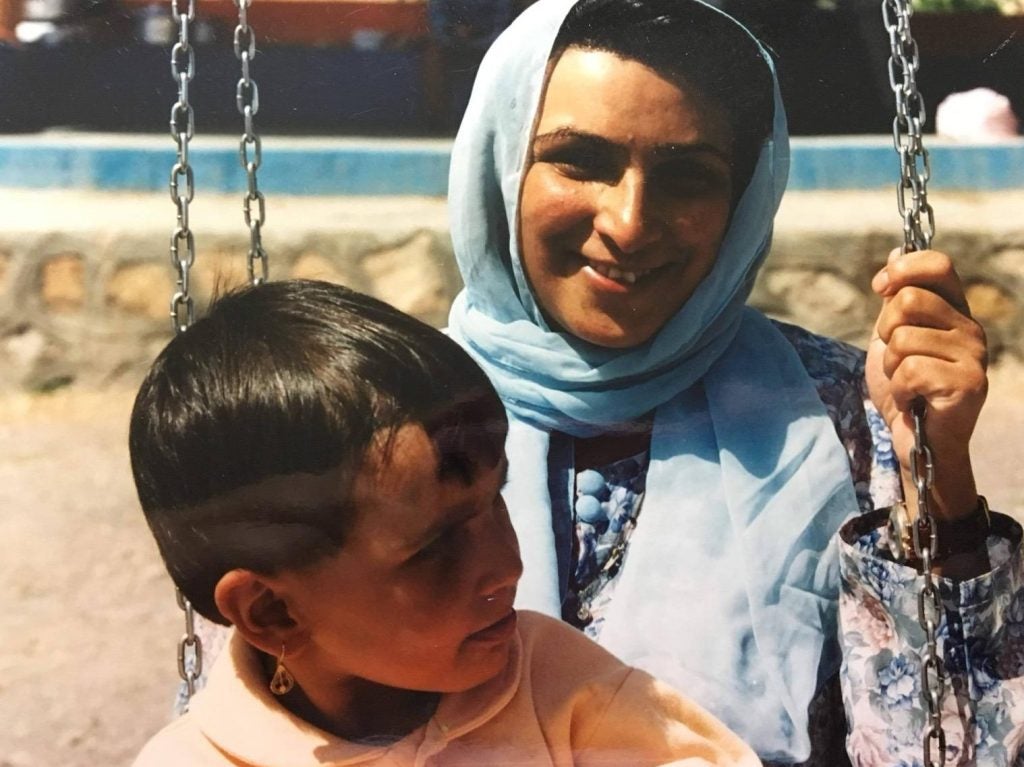 A photo from 2023 of a mother wearing a hijab and sitting on a swing with her daughter on her lap