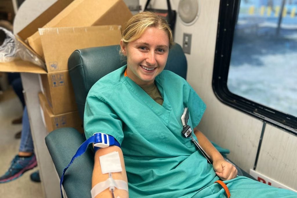 Young woman in nursing scrubs donating blood