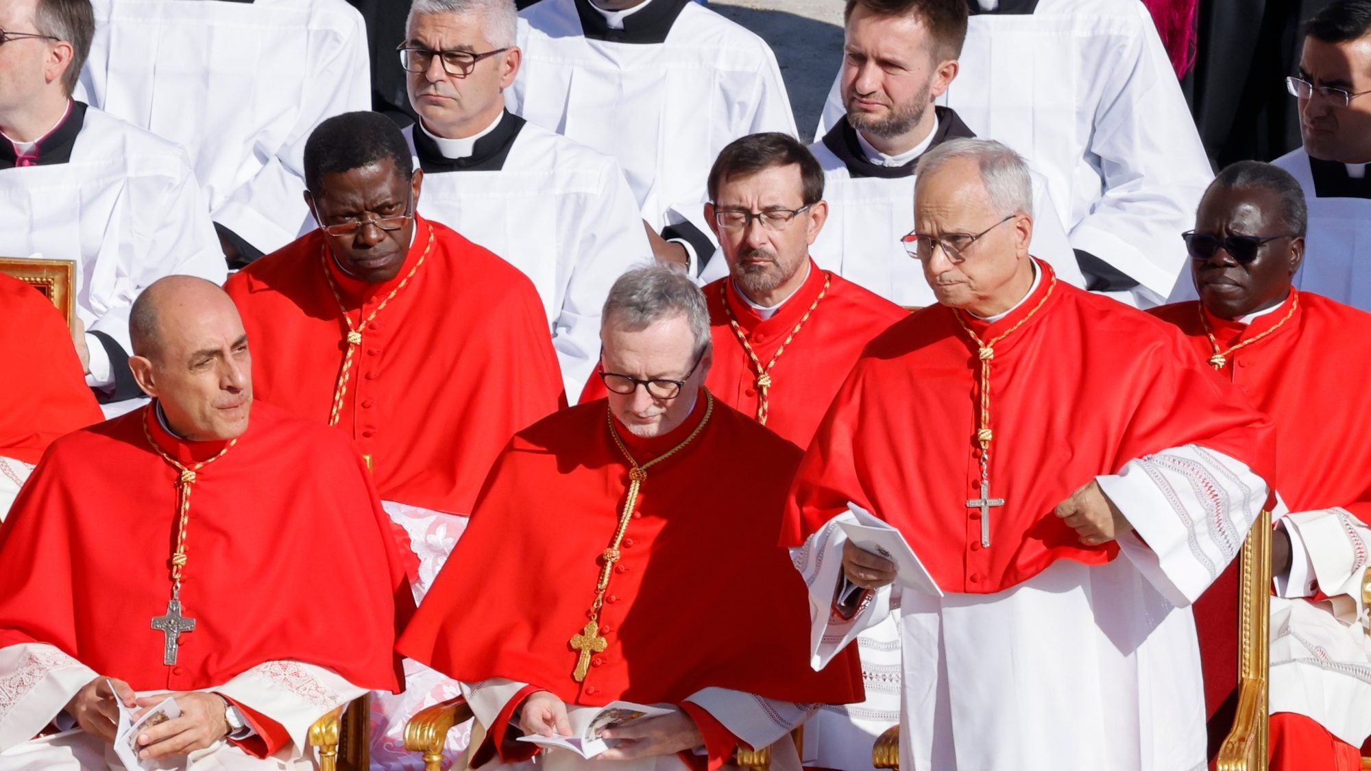 A group of cardinals of red robes talk together