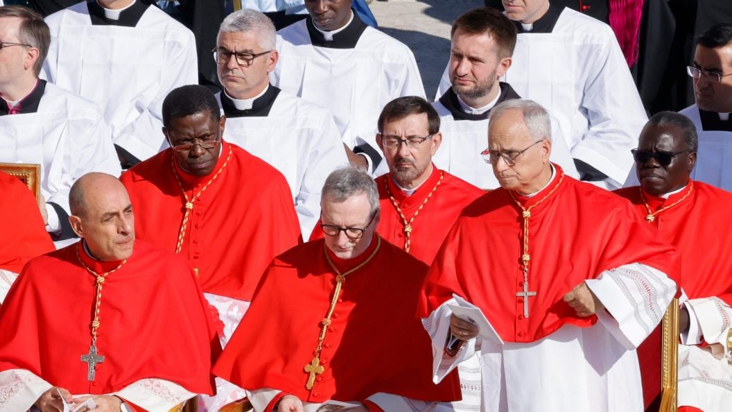 A group of cardinals of red robes talk together