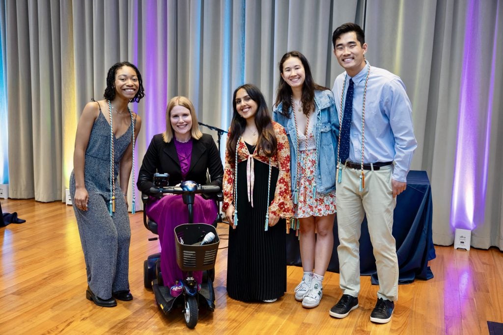 A woman in a wheelchair with four students
