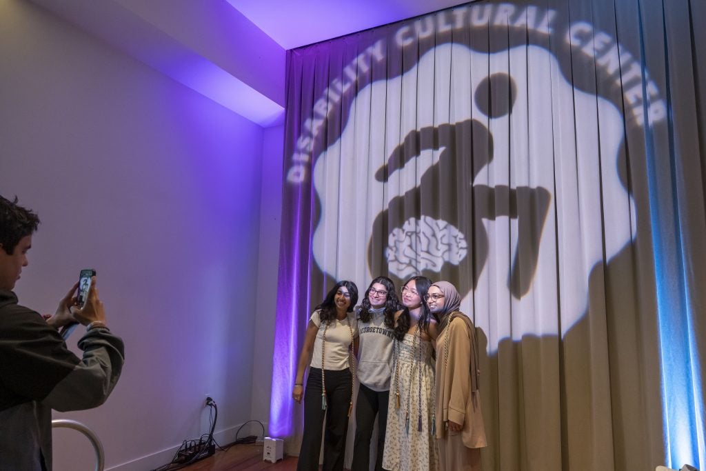 Students post for a photo in front of a projection for the Disability Culture Center