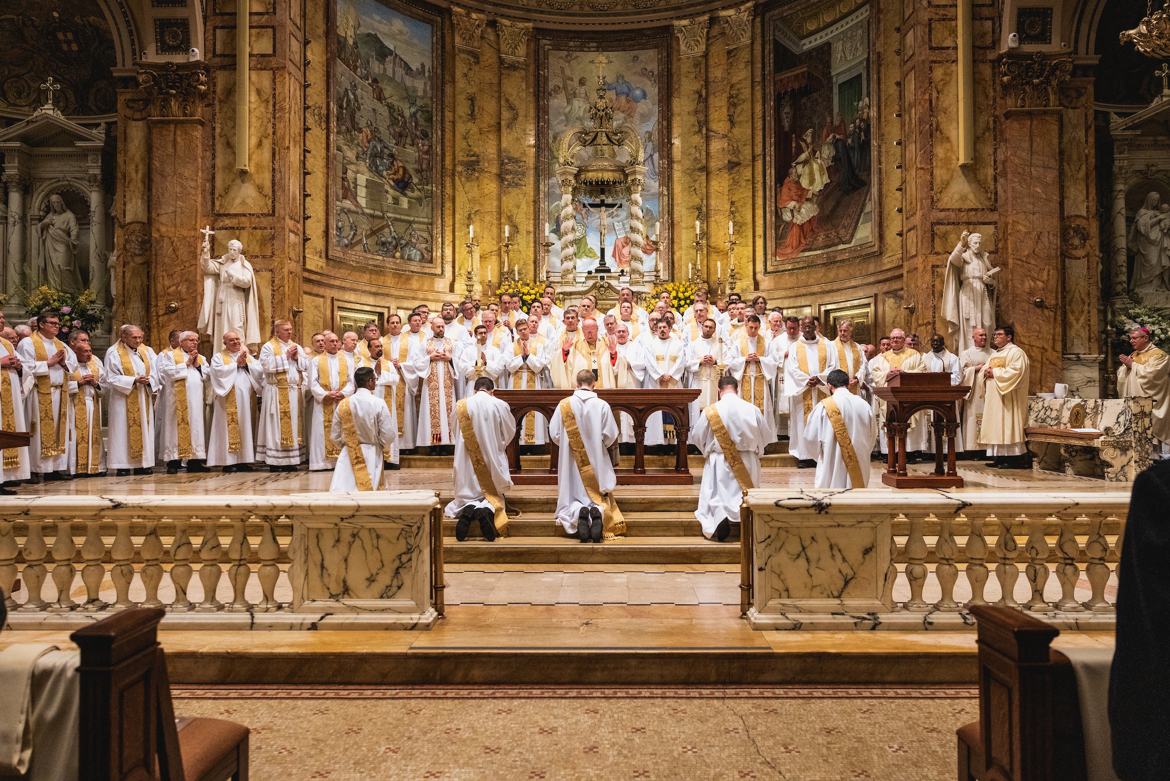 Five candidates for ordination kneel before the altar and other priests