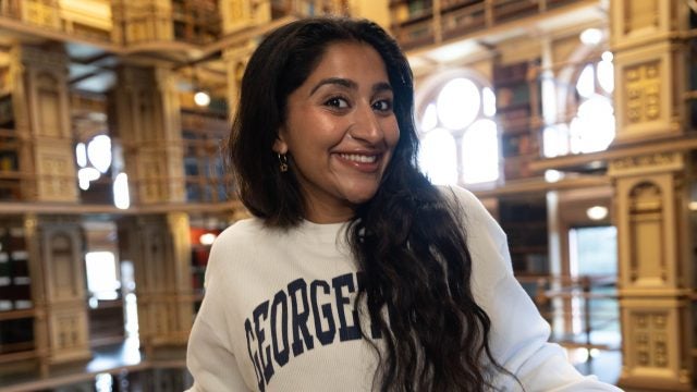 Harnoor in Riggs library in a Georgetown sweatshirt