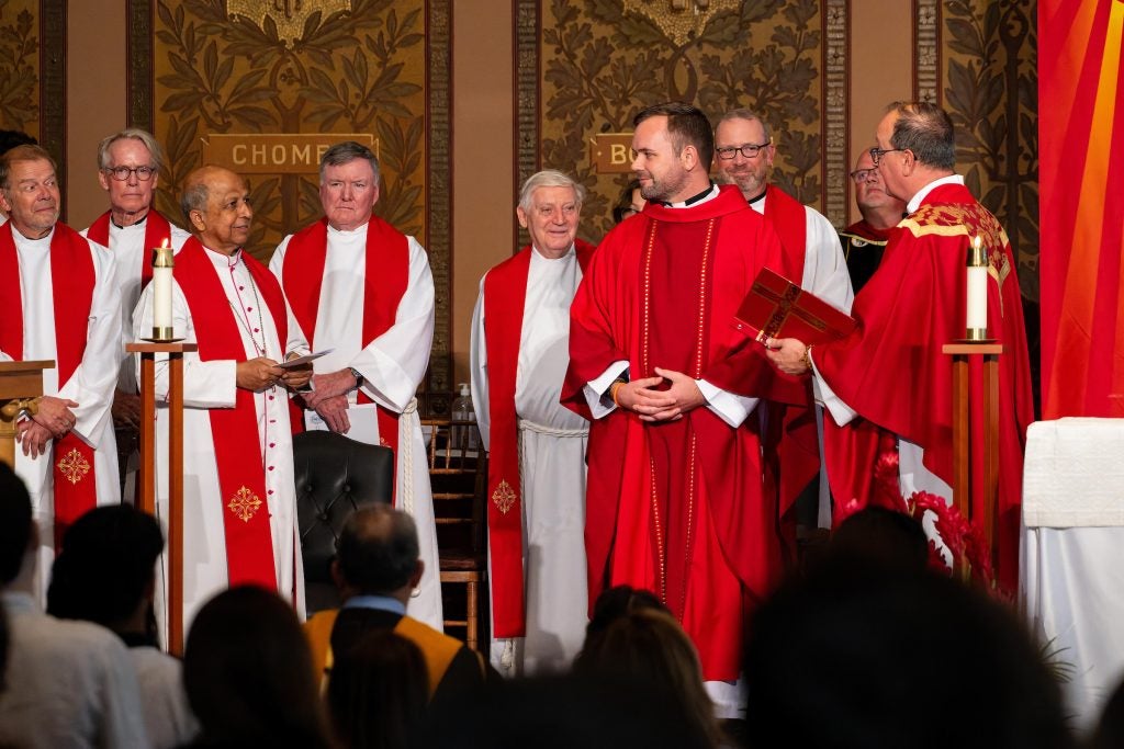 A group of priests wear white and red on an altar during Mass