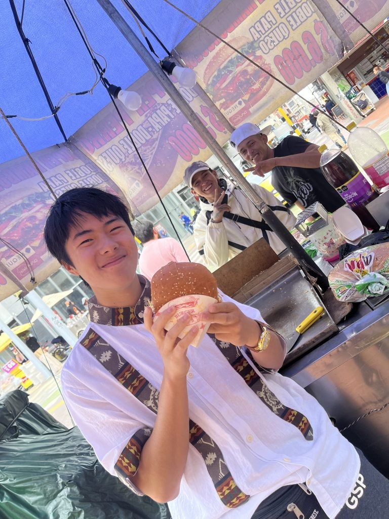 Jeremy holding a burger at a street vendor in Quito