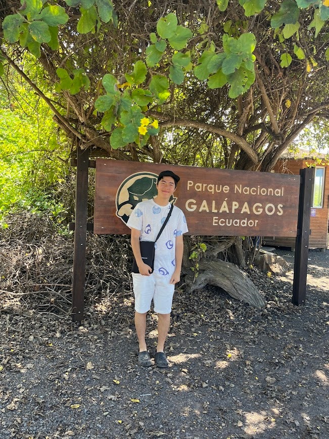 Jeremy standing in front of a sign for the Galapagos National Park