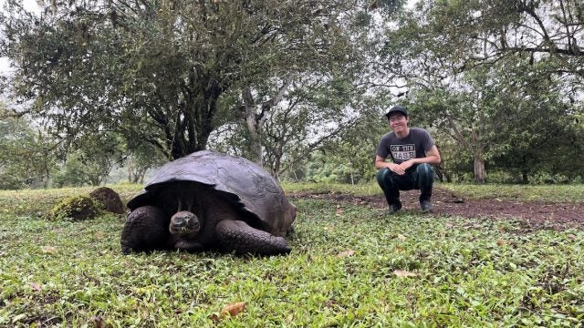 Jeremy squatting next to a tortoise