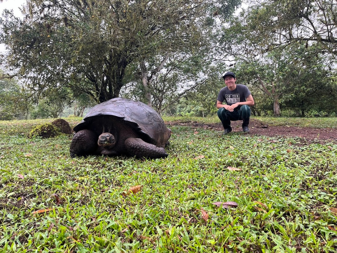 Jeremy squatting next to a tortoise