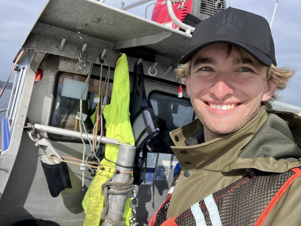 A male student grins on a fishing boat