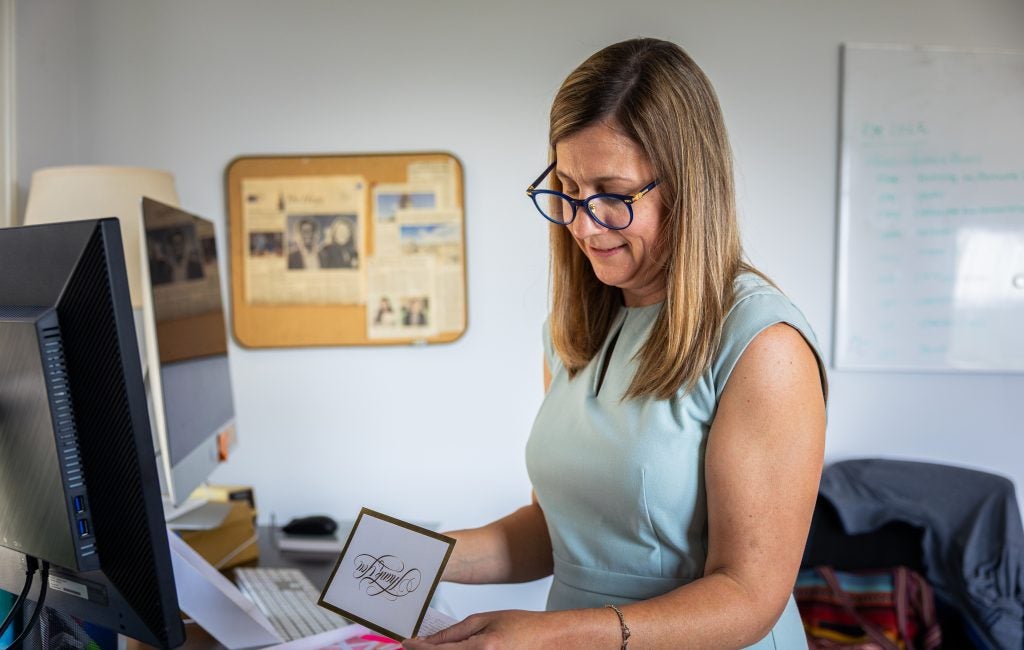 A woman in a light blue dress reads a thank-you card