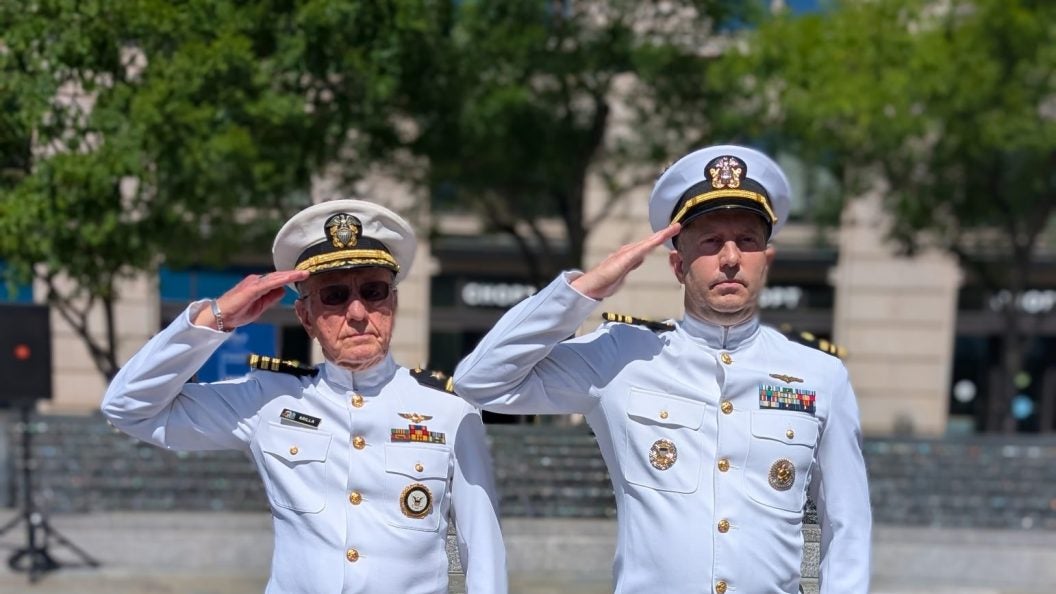 Two men in white Navy uniforms salute