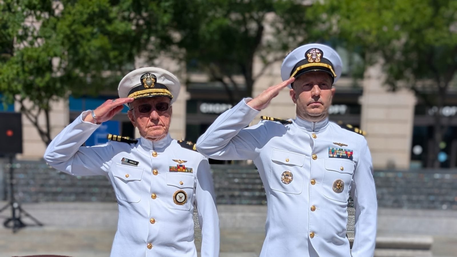 Two men in white Navy uniforms salute