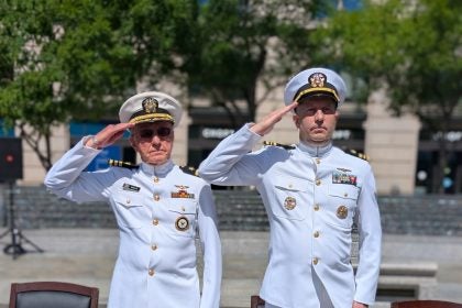 Two men in white Navy uniforms salute