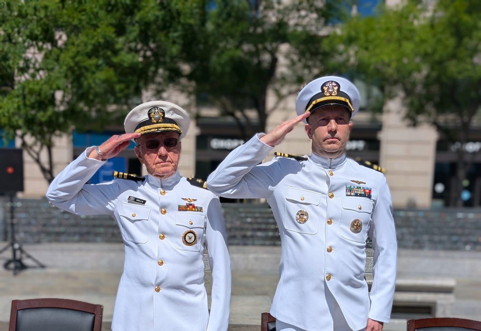 Two men in white Navy uniforms salute