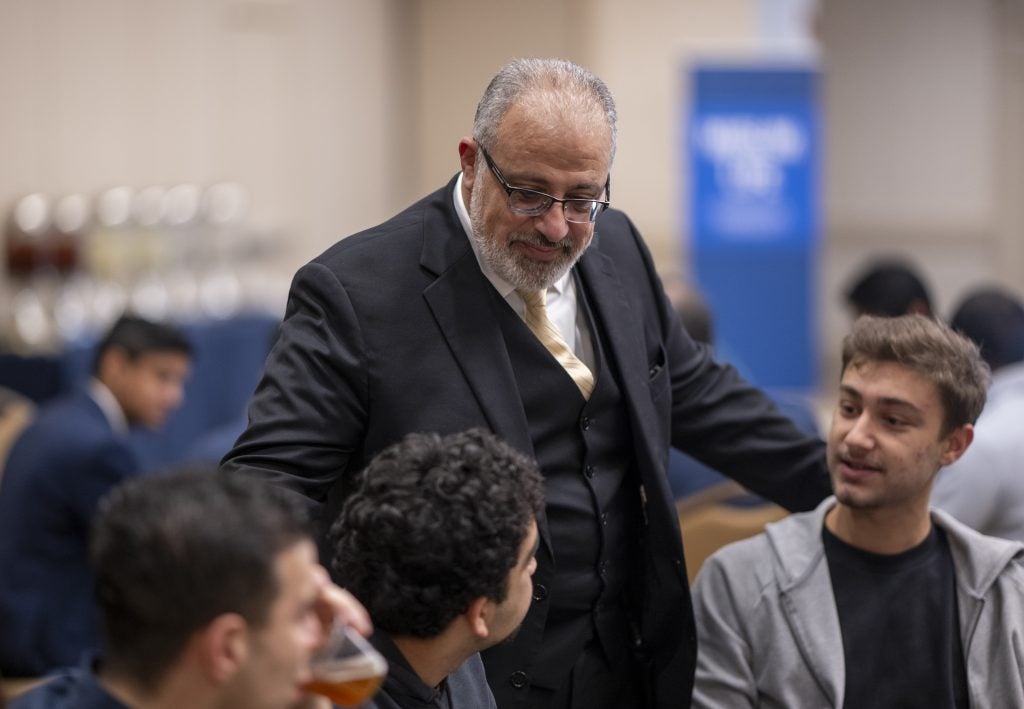 Imam Hendi in a suit talking with students