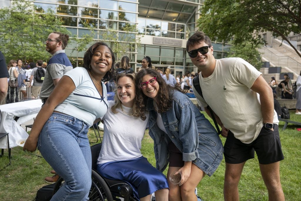 A group of students pose together in front of a glass building