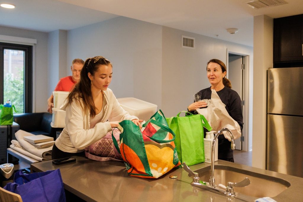 A student and her parents unpack bags in her new apartment